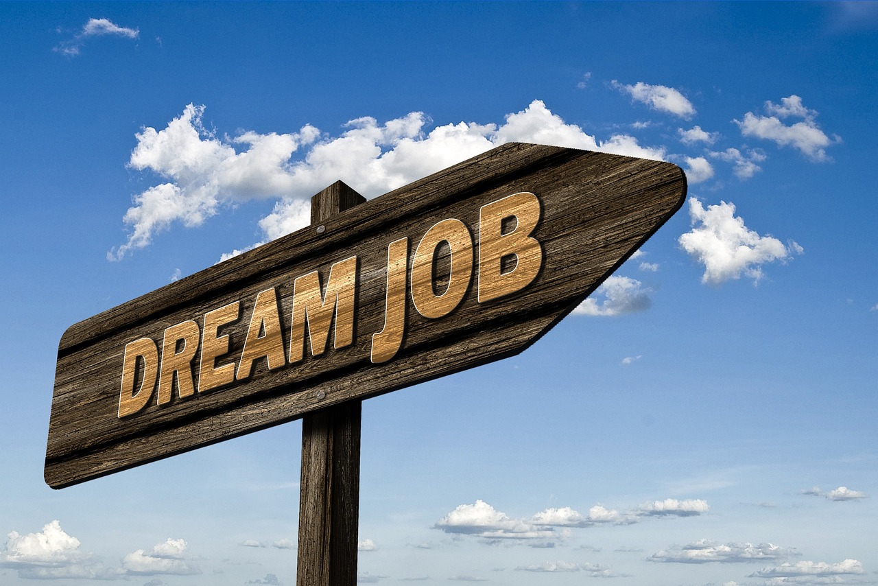 Zdjęcie przedstawia drogowskaz z napisem dream job (wymarzona praca) na tle nieba. 