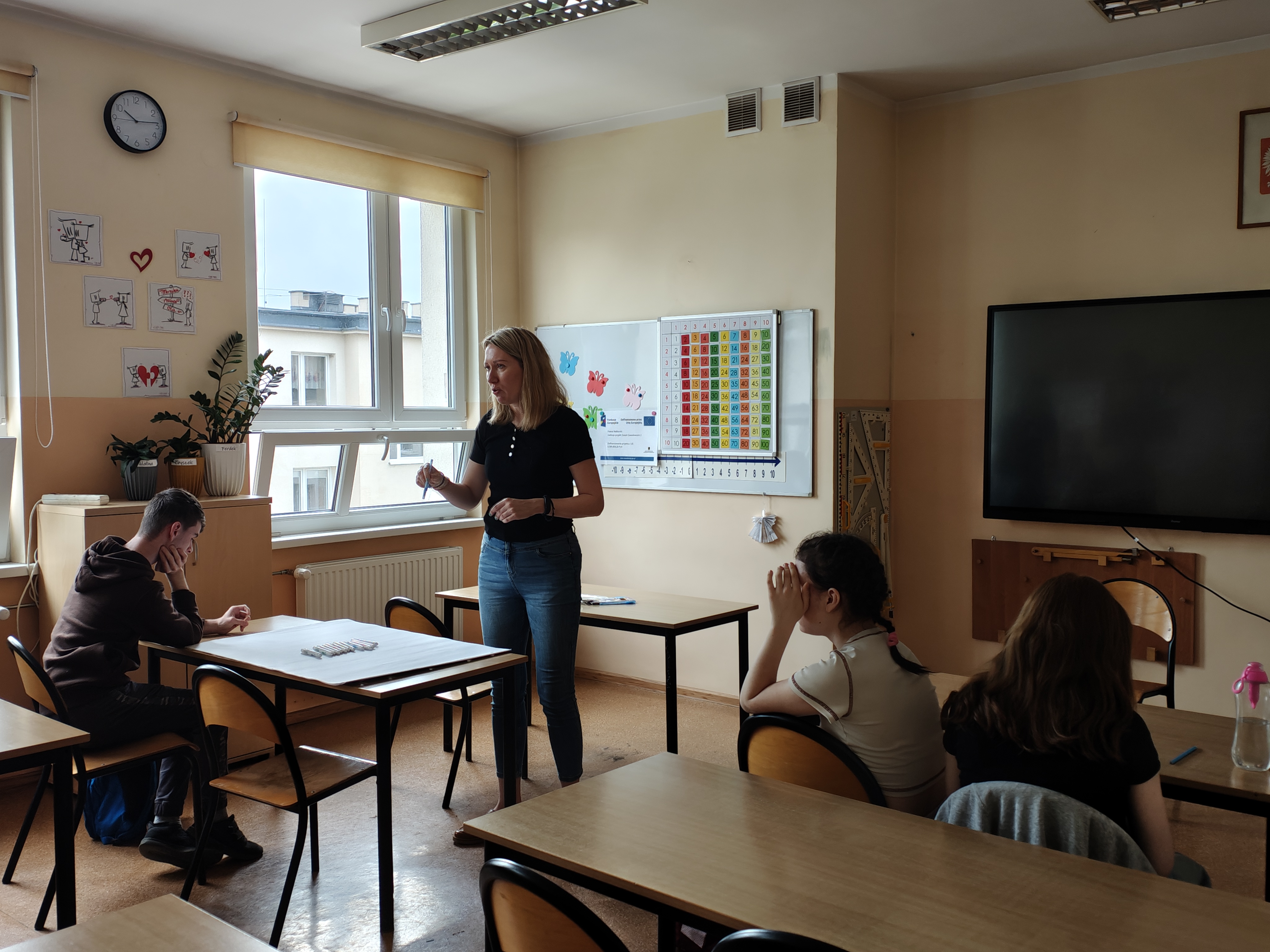 Zdjęcie przedstawia Koordynatorkę Powiatową objaśniającą młodzieży instrukcję zadania na arkuszach służącego do rozpoznawania swoich talentów oraz cech charakteru  