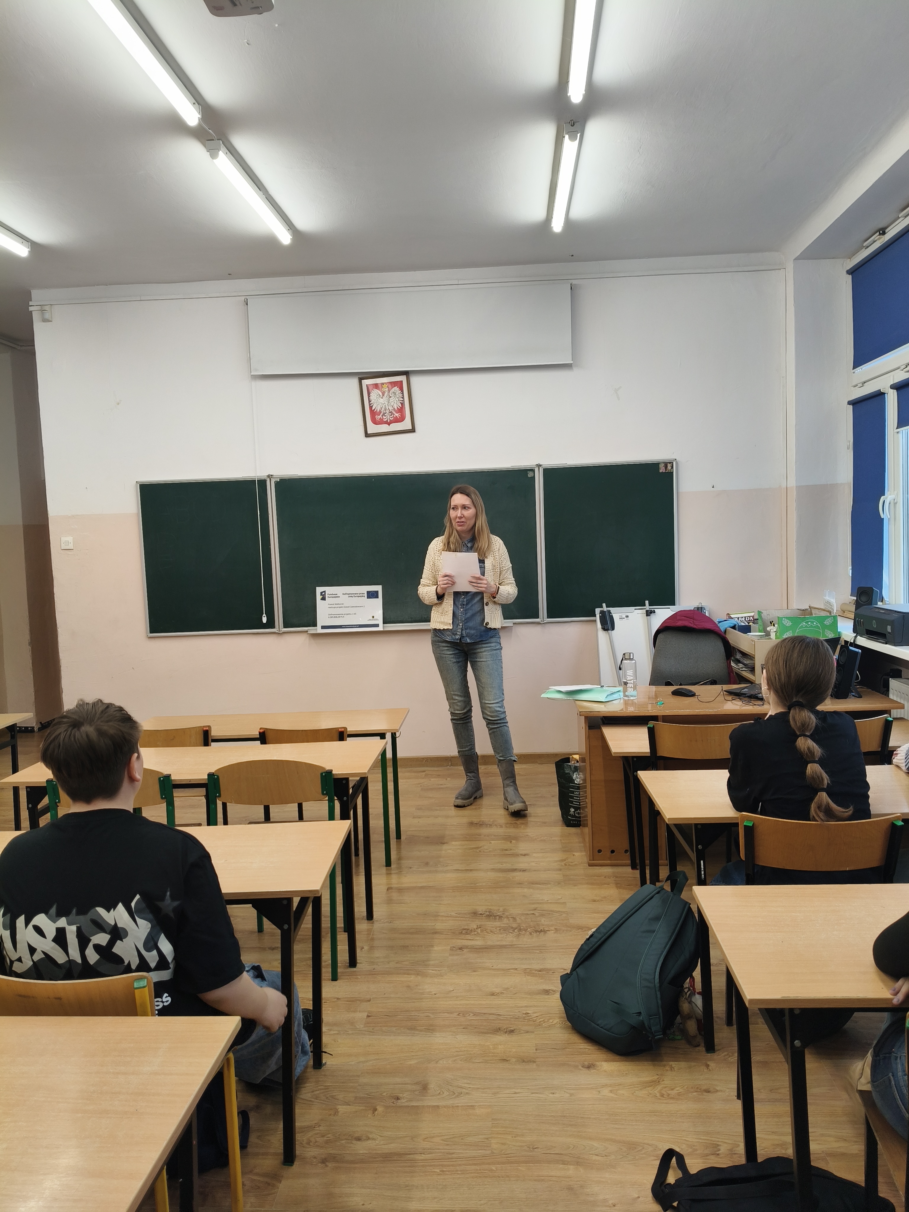 Zdjęcie przedstawia Koordynatorkę Powiatową stojącą przy tablicy w klasie i rozmawiającą z uczniami o planowaniu kariery 